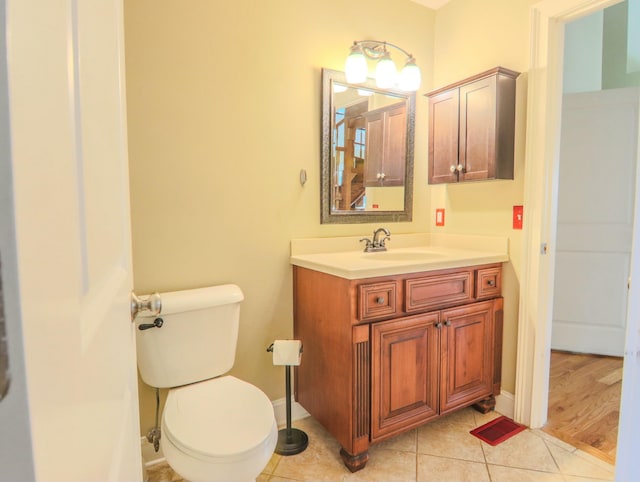 half bathroom with baseboards, visible vents, toilet, tile patterned floors, and vanity