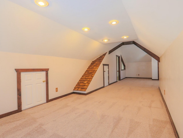 bonus room featuring light colored carpet, vaulted ceiling, and baseboards