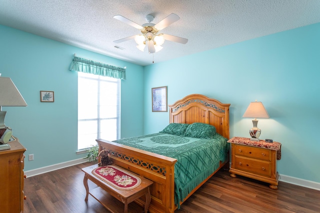 bedroom with a textured ceiling, dark wood finished floors, visible vents, and baseboards