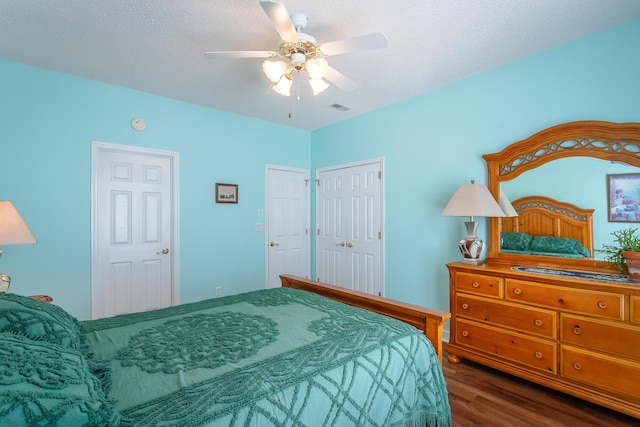 bedroom with a textured ceiling, ceiling fan, wood finished floors, and visible vents