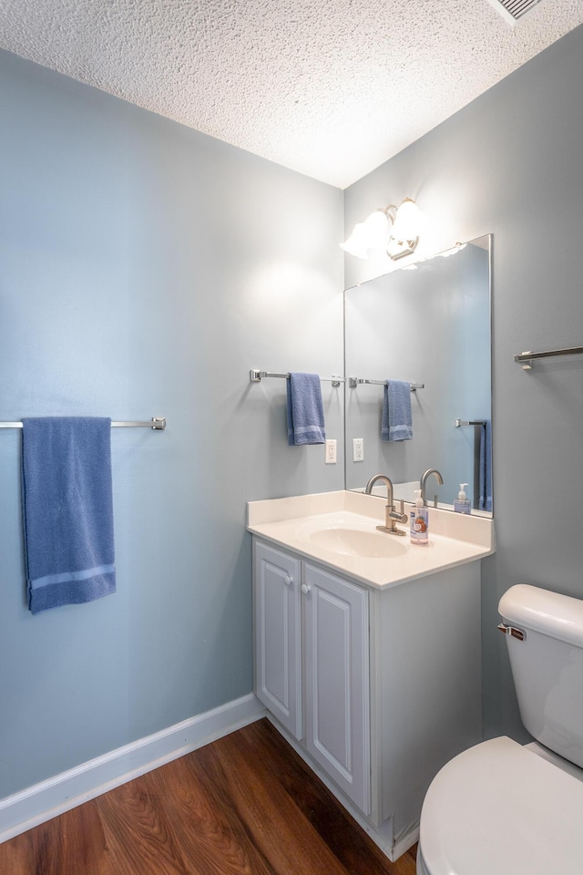 bathroom with toilet, baseboards, wood finished floors, and vanity