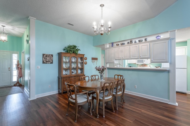 dining space featuring baseboards, visible vents, dark wood-type flooring, an inviting chandelier, and a textured ceiling