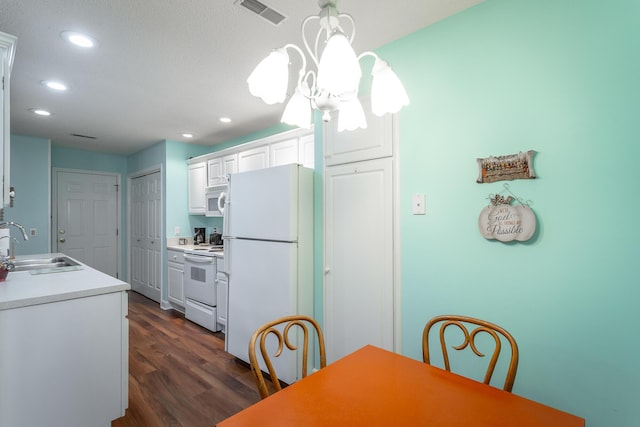 kitchen with white appliances, visible vents, white cabinets, dark wood-style flooring, and a sink