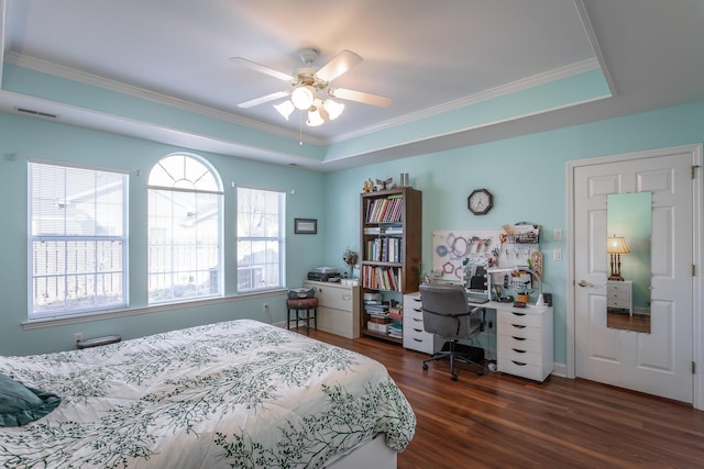 bedroom featuring ceiling fan, a tray ceiling, dark wood-style flooring, and crown molding