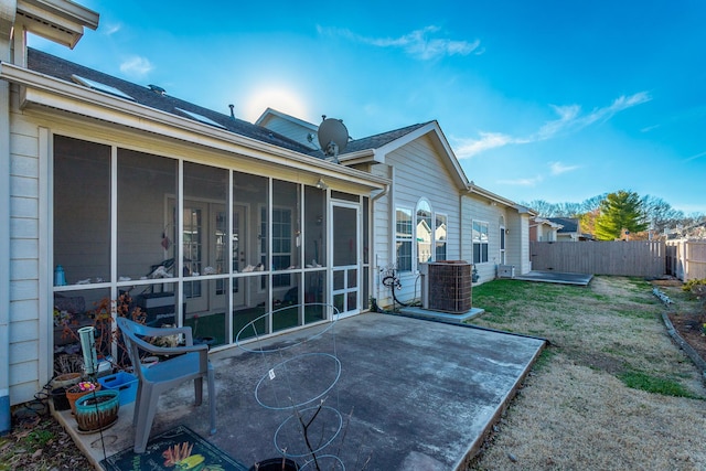 exterior space with central air condition unit, a lawn, a sunroom, a patio area, and fence