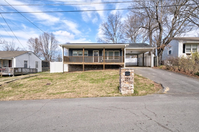 view of front facade featuring aphalt driveway, an attached carport, fence, and a front lawn