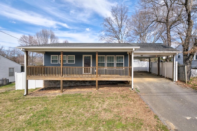 single story home featuring a porch, a front yard, fence, an attached carport, and driveway