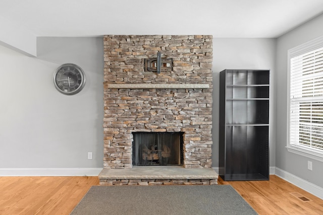 unfurnished living room with baseboards, a fireplace, visible vents, and wood finished floors