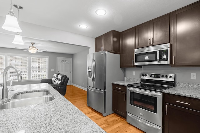 kitchen featuring dark brown cabinets, stainless steel appliances, a sink, and light wood-style flooring