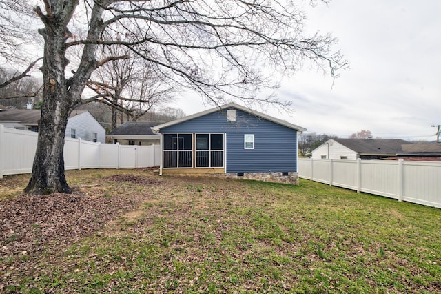 rear view of property featuring a sunroom, a fenced backyard, and a yard