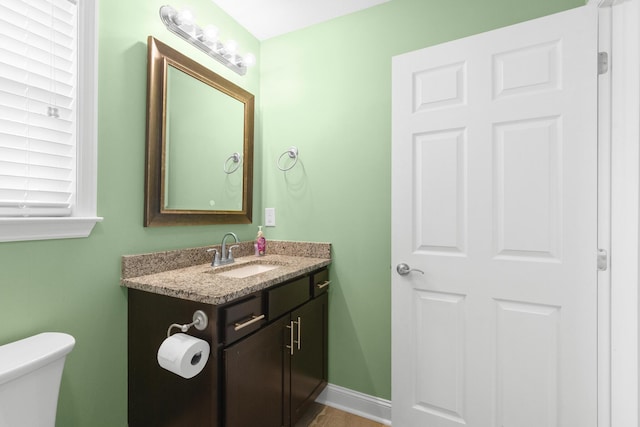 half bathroom featuring baseboards, vanity, and toilet