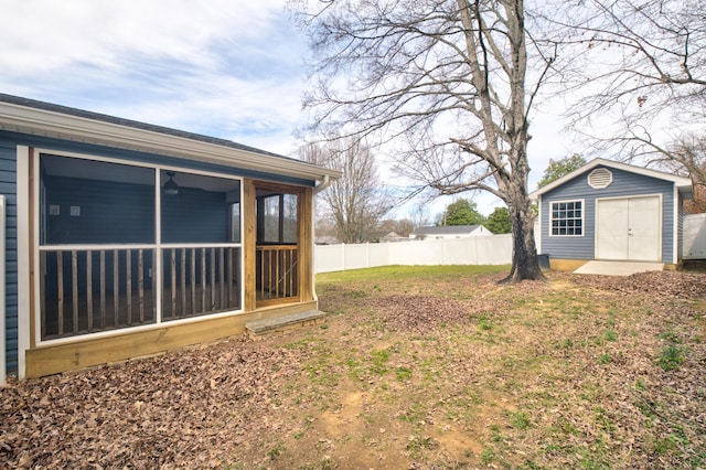 view of yard with a sunroom, fence, and an outbuilding