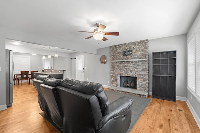 living area with visible vents, a fireplace, light wood-style flooring, and ceiling fan