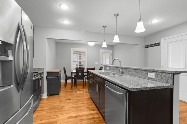 kitchen with appliances with stainless steel finishes, a sink, dark brown cabinetry, and light wood-style floors