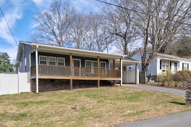 view of front of property featuring driveway, covered porch, fence, a front lawn, and a carport