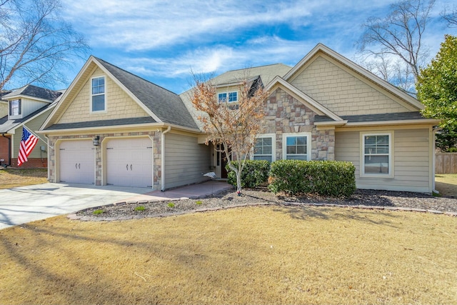 craftsman-style home with a shingled roof, concrete driveway, a garage, stone siding, and a front lawn