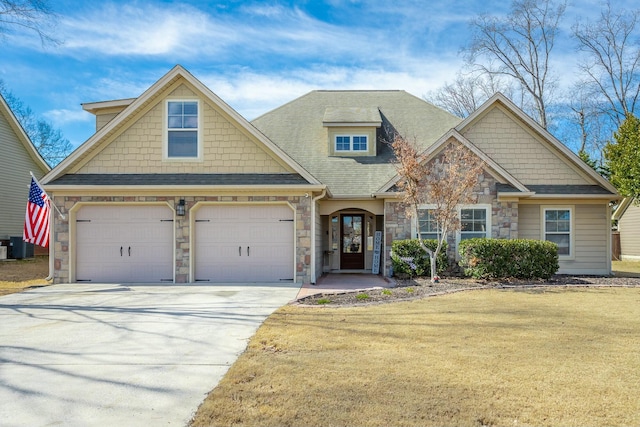 craftsman-style house featuring an attached garage, a front yard, cooling unit, stone siding, and driveway