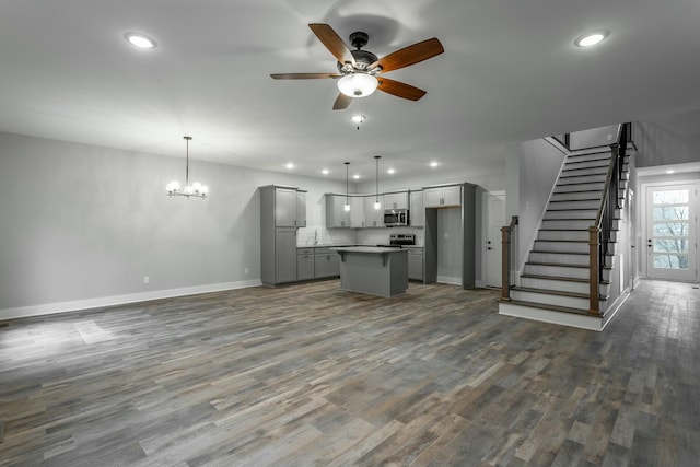 kitchen with dark wood finished floors, stainless steel microwave, open floor plan, a center island, and gray cabinets