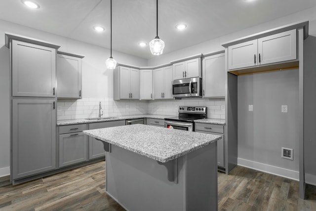 kitchen featuring dark wood-type flooring, a sink, appliances with stainless steel finishes, gray cabinets, and tasteful backsplash