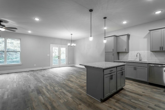 kitchen featuring open floor plan, stainless steel dishwasher, a sink, and gray cabinetry