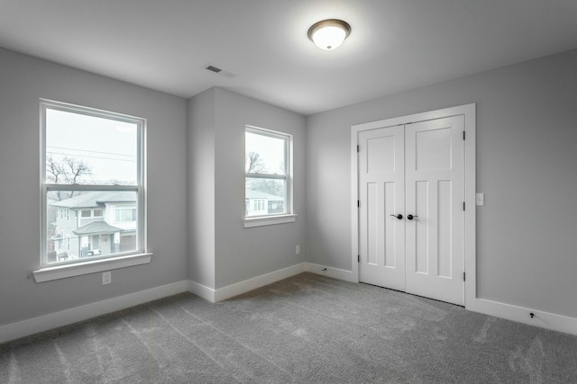 unfurnished bedroom with carpet floors, visible vents, and baseboards