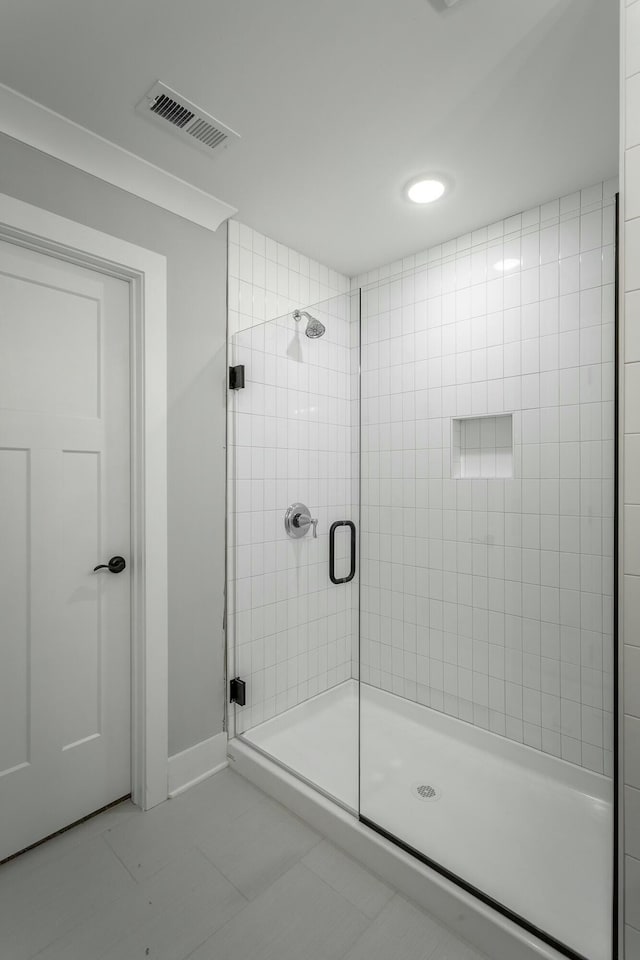 bathroom with a stall shower, visible vents, baseboards, and tile patterned floors