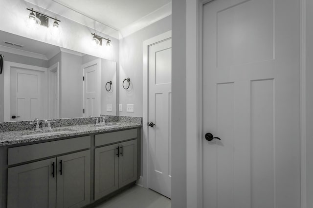 full bath featuring double vanity, a sink, visible vents, and crown molding