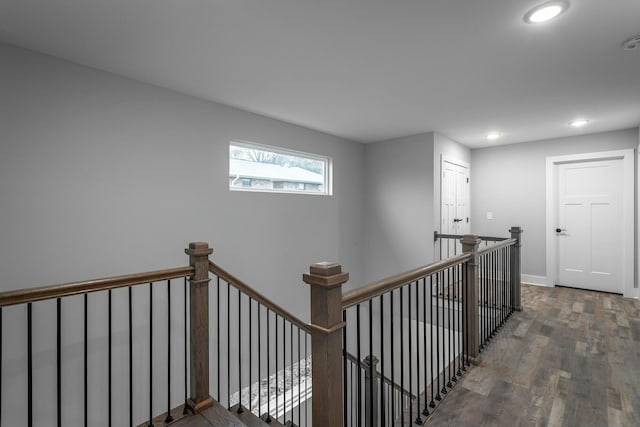 corridor featuring baseboards, wood finished floors, an upstairs landing, and recessed lighting