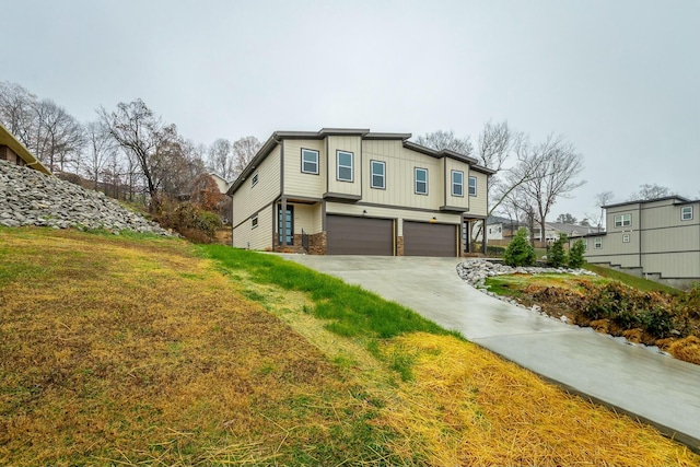 view of front facade featuring an attached garage, driveway, board and batten siding, and a front yard