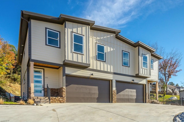 view of front of house with a garage, driveway, board and batten siding, and fence