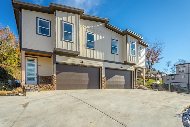 view of front of property featuring driveway, board and batten siding, an attached garage, and fence