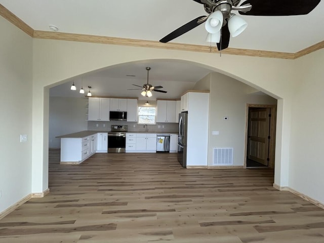 kitchen featuring arched walkways, light wood finished floors, stainless steel appliances, visible vents, and white cabinets