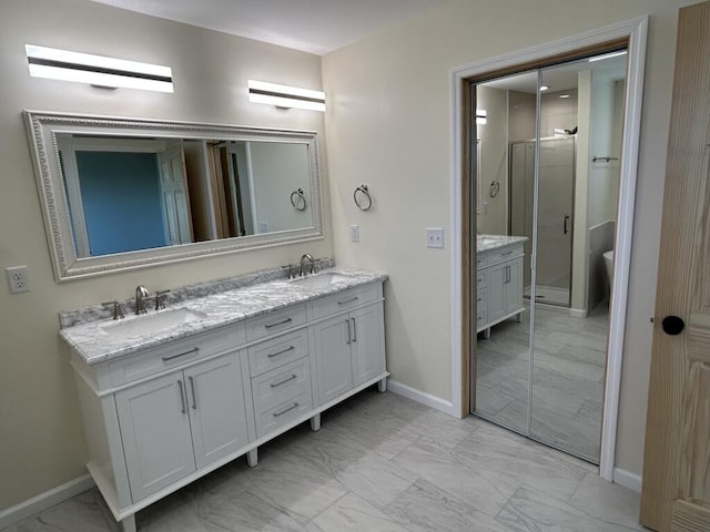 bathroom featuring marble finish floor, double vanity, a stall shower, and a sink