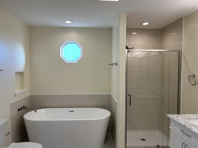 bathroom with a soaking tub, toilet, a shower stall, and vanity