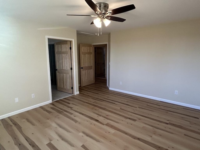 spare room with wood finished floors, a ceiling fan, and baseboards