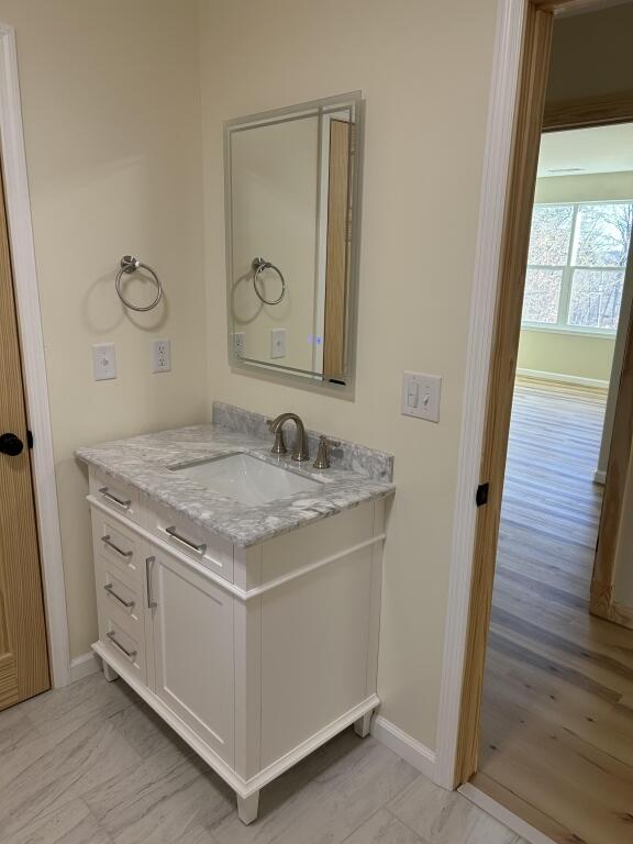 bathroom with marble finish floor, vanity, and baseboards