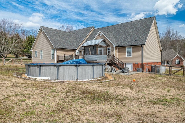 back of property with a gate, fence, an outdoor pool, and a lawn