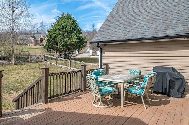 wooden deck with outdoor dining area, a yard, grilling area, and fence