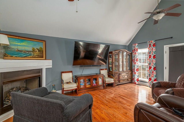 living room featuring a ceiling fan, a fireplace, high vaulted ceiling, and wood finished floors