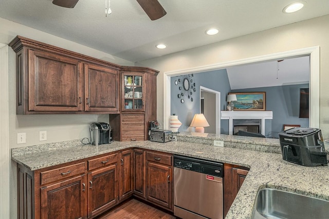 kitchen featuring light stone counters, a fireplace, dark wood-style floors, a ceiling fan, and dishwasher