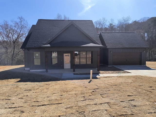 view of front of home with driveway, an attached garage, a shingled roof, and board and batten siding