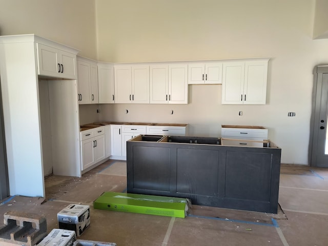 kitchen with a high ceiling, white cabinetry, and a center island