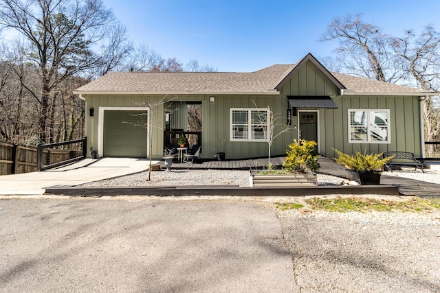 ranch-style house with a garage, driveway, roof with shingles, fence, and board and batten siding