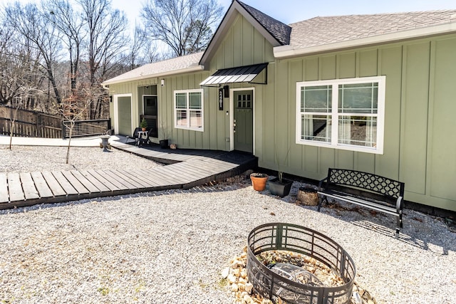 back of house with roof with shingles, an attached garage, board and batten siding, a standing seam roof, and fence