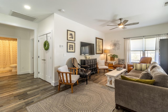 living area with dark wood-style floors, ceiling fan, visible vents, and baseboards