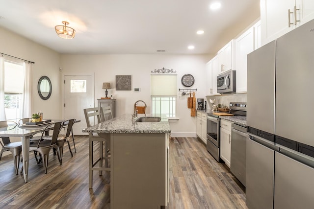 kitchen with stainless steel appliances, a wealth of natural light, a sink, and light stone countertops