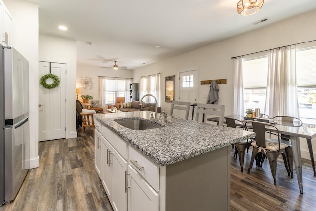 kitchen featuring visible vents, dark wood finished floors, a sink, and freestanding refrigerator