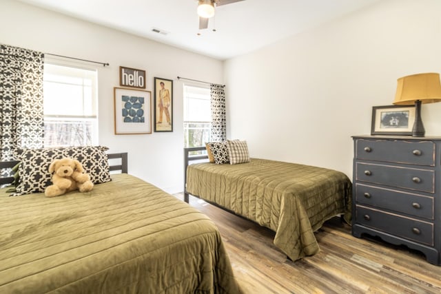 bedroom with a ceiling fan, multiple windows, visible vents, and wood finished floors