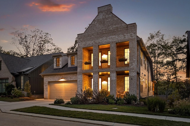 view of front of home with a yard, concrete driveway, brick siding, and a balcony