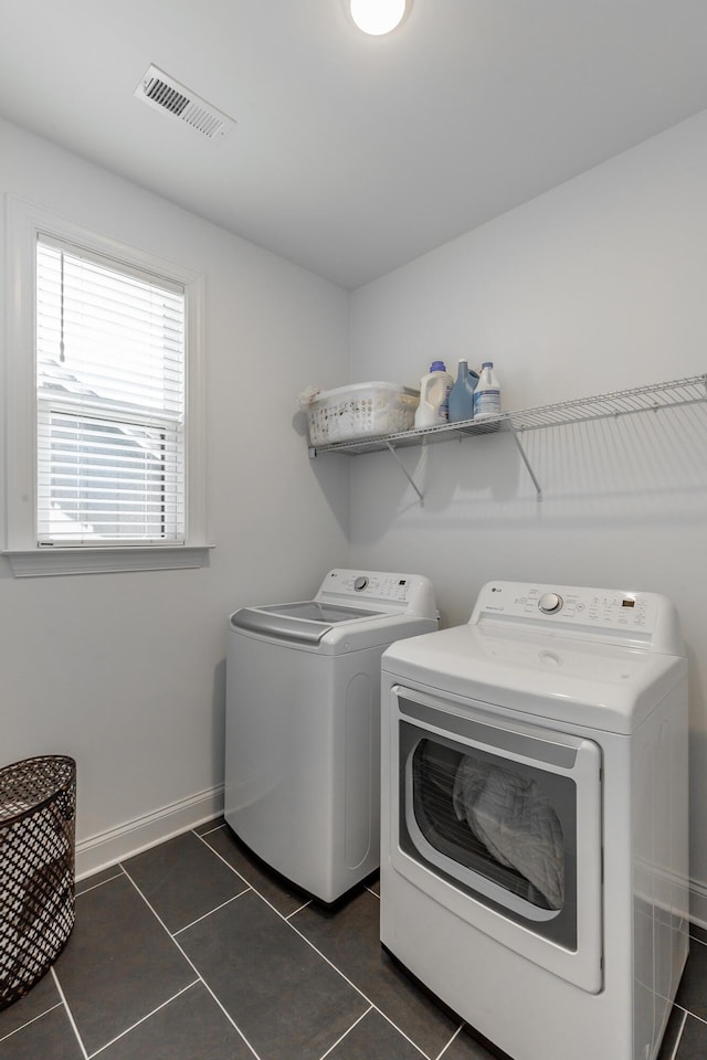 clothes washing area with laundry area, baseboards, visible vents, dark tile patterned flooring, and separate washer and dryer